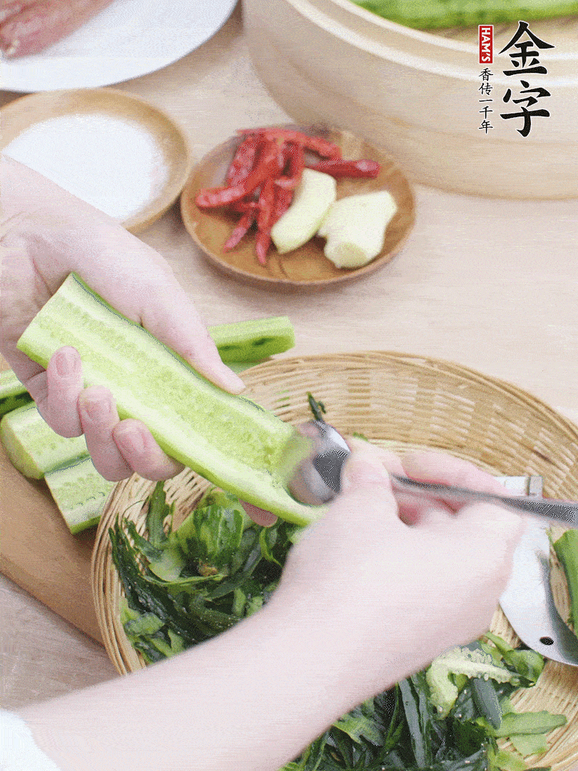 黃瓜削皮，對半切開，勺子挖去內(nèi)瓤，斜刀切片。青蒜斜刀切段。